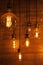 On a dark wooden background hang burning light bulbs of different shapes