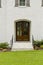 Dark wooden front door with a small arch and black rails with green grass