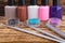 On a dark wooden table, items for manicure, multi-colored nail polishes, lined up, rhinestones and brushes