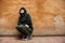 Dark young woman sad crouched near urban wall portrait