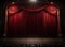 Darkened empty movie theatre and stage with the red curtains drawn viewed over rows of vacant seats from the rear