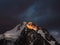 Darkness mountain landscape with great snowy mountain lit by dawn sun among dark clouds. Awesome alpine scenery with high mountain