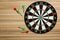Dart board with color arrows on wooden background, top view. Space for