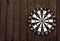 Dart board on dark wood background with copy space. A dart in the bull`s-eye. Achieving the goal. Success of hitting the target