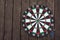 Dart board on dark wood background with copy space. A dart in the bull`s-eye. Achieving the goal. Success of hitting the target