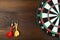 Dartboard and darts on a wooden background