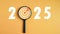 Dartboard icon in a magnifying glass centered on the number 2025 on a yellow background. Represents the goal setting for 2025,