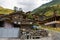 Dartlo village view with old, stone houses and people in the fields forested mountains background