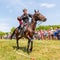 A dashing Cossack knocks down the sword of a bottle of water on a horse