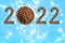 Date 2022 made of dry food and a round metal bowl full of crunchy dry food for dogs or cats on a blue background with