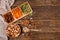 Dates, dried apricots and kiwis in a Compartmental dish and assortment of nuts in wooden bowl on a dark wooden table