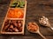 Dates, dried apricots and kiwis in a Compartmental dish and nuts in a wooden spoon on a dark wooden table. Copy space