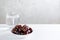 Dates and a glass of water on white wooden table.