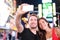 Dating young couple happy in love taking selfie photo on Times Square, New York City at night. Beautiful young multiracial tourist