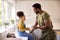 Daughter With American Army Father In Uniform On Home Leave Drinking Juice In Kitchen