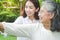 Daughter caring for elderly Asian mother Both of them exercised in the front garden.