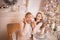 Daughter closes her mom`s eyes made a surprise near the Christmas tree in a festive interior