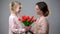 Daughter giving flowers to mother, womans day congratulations, surprise gift