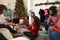 Daughter Giving Mother Gift As Multi Generation Family Celebrate Christmas At Home Together