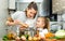 Daughter helping cooking soup and mother add pepper to pan