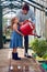 Daughter Helping Father To Water Tomato Plants In Greenhouse At Home