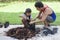 Daughter helps father plant trees in the garden. It is a family activity.