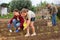 Daughter helps mom to water plants from a watering can in farm field