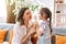 Daughter kissed her mother and gave gift with flowers while sitting on the sofa, mother\'s day