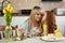 Daughter kisses her mother. Woman and little girl paint eggs and make decorations for the Easter holidays.