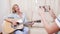 Daughter making a video with her mother playing on an acoustic guitar