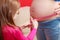 Daughter measuring pregnant woman belly with tape