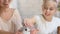 Daughter and mother in headbands with bunny ears stroking little white rabbit