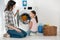 daughter in pink t-shirt and mother in grey shirt sitting on floor near washer with clothes