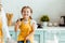 Daughter in polka dot yellow apron holding balloon whisk next to mother in kitchen