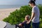 Daughter push the wheel-chair forward for her mother in front of the beach