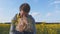 The daughter runs to meet his father with rapeseed flowers.