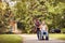 Daughter and senior man in wheelchair on walking green nature