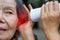 Daughter talking to hearing impaired elderly woman , using paper tube