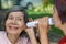 Daughter talking to hearing impaired elderly woman , using paper tube