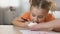 Daughter tasting sweet dessert from mother hand, drawing by pencil on table