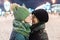 Daughter teenager gently kisses his mother in the nose while standing on a nightly brightly lit street in winter