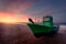 Dawn behind a boat located on the shore of the beach