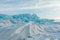 Dawn in the blue hummocks of ice lake baikal, in a snowy field i