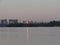 Dawn cityscape with reflection in the river water of bright orange flare in the window of the house.