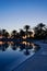 Dawn at the hotel near the pool. Silhouettes of palm trees reflected in the water, sunrise. Rest at the hotel, travel, tourism