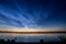 Dawn on lake. Feathered clouds glow at dawn