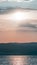 Dawn over sea and mountains. Calm serene view of sunrise on summer beach. Minimal landscape. Nature vertical background