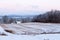 Dawn rural winter landscape with small sheds in field on St. Lawrence River coastline