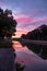 Dawn's Drama: Vibrant Sunrise Reflects in Canal, Framed by Tree Silhouettes