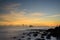 Dawn\\\'s Embrace: Sunburst and Rocky Shoreline at the Beach.
